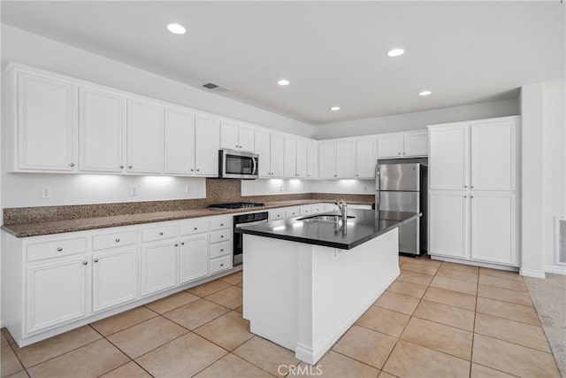 kitchen with white cabinets, light tile patterned flooring, an island with sink, and appliances with stainless steel finishes