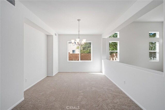 empty room with carpet flooring and a chandelier