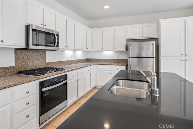 kitchen with white cabinets, light tile patterned floors, stainless steel appliances, and sink