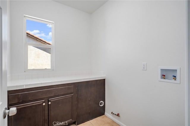 washroom featuring cabinets, hookup for a washing machine, light tile patterned floors, and hookup for a gas dryer