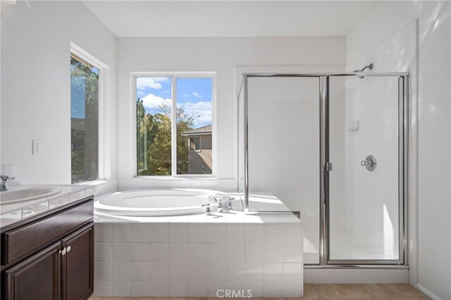 bathroom featuring plus walk in shower, tile patterned flooring, and vanity