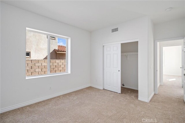 unfurnished bedroom with light carpet and a closet