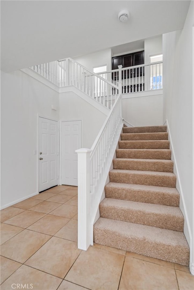 staircase featuring tile patterned flooring and a high ceiling