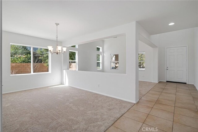 carpeted spare room with a notable chandelier