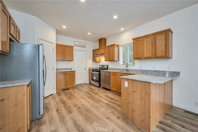 kitchen with light stone countertops, light hardwood / wood-style flooring, stainless steel appliances, and sink