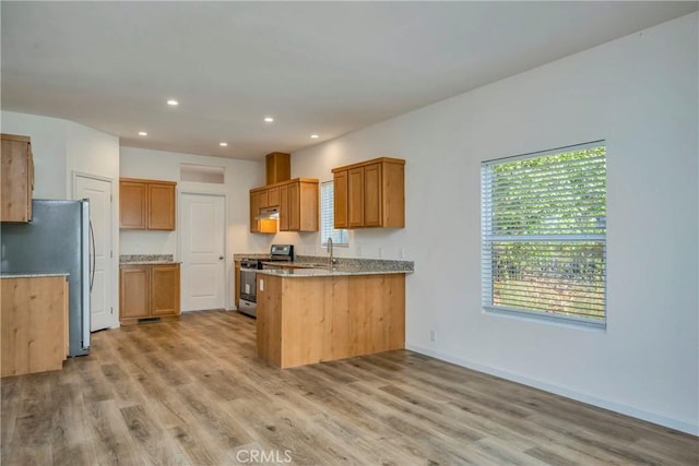 kitchen featuring kitchen peninsula, light wood-type flooring, stainless steel appliances, and sink