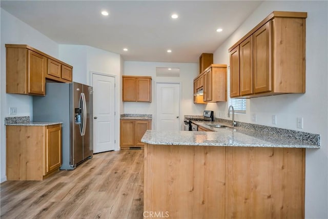 kitchen with sink, light stone counters, light hardwood / wood-style flooring, kitchen peninsula, and appliances with stainless steel finishes