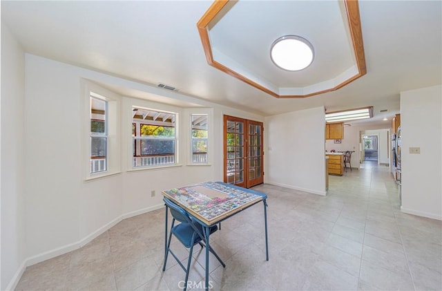 tiled dining space with french doors and a tray ceiling