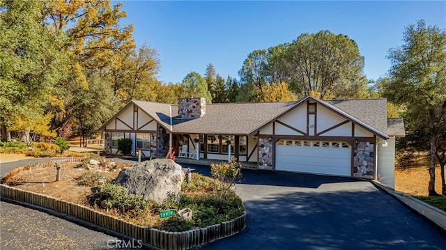 english style home featuring covered porch and a garage