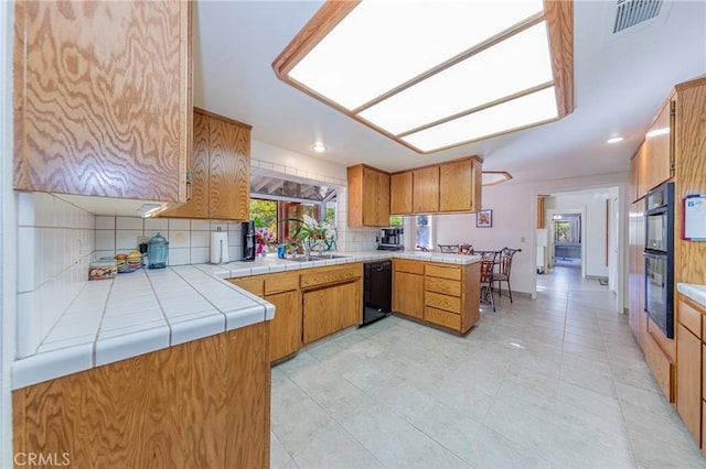 kitchen featuring kitchen peninsula, decorative backsplash, sink, and tile countertops