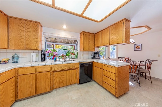 kitchen featuring tile countertops, a wealth of natural light, and black dishwasher