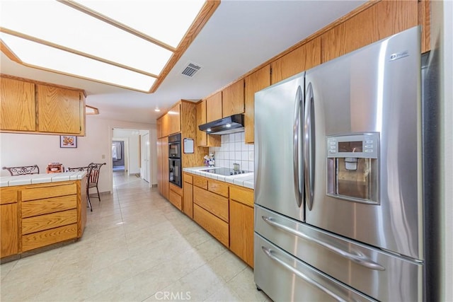 kitchen featuring black appliances, tile counters, decorative backsplash, and light tile patterned floors