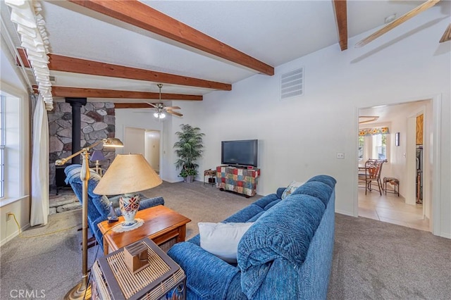 living room featuring carpet flooring, lofted ceiling with beams, a wood stove, and ceiling fan