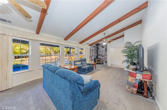 carpeted living room with vaulted ceiling with beams, ceiling fan, and a wood stove