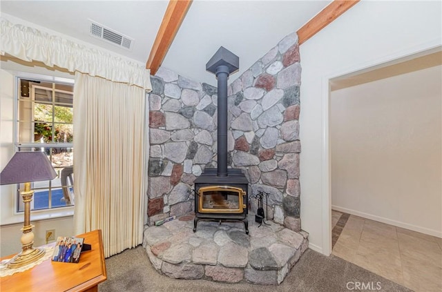 room details with carpet flooring, beam ceiling, and a wood stove