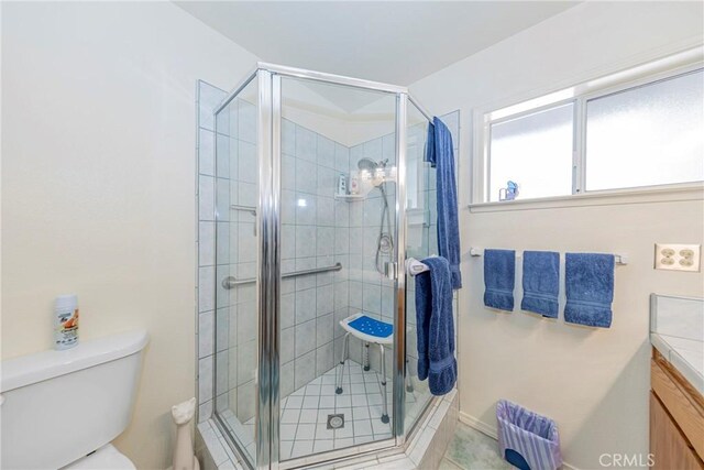 bathroom featuring tile patterned flooring, toilet, an enclosed shower, and vanity