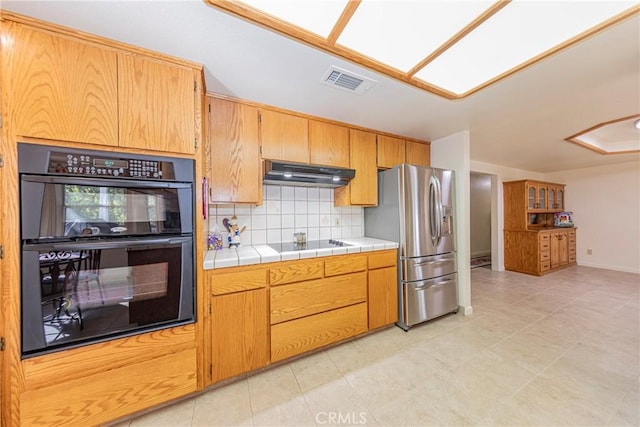 kitchen with backsplash, tile counters, light tile patterned flooring, and black appliances