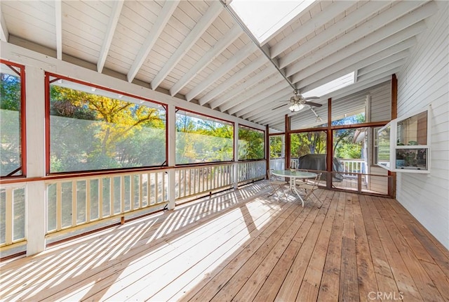 unfurnished sunroom featuring ceiling fan, vaulted ceiling with skylight, and a healthy amount of sunlight