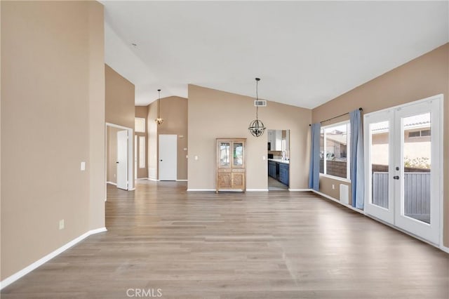 unfurnished living room with hardwood / wood-style floors, a wealth of natural light, and french doors