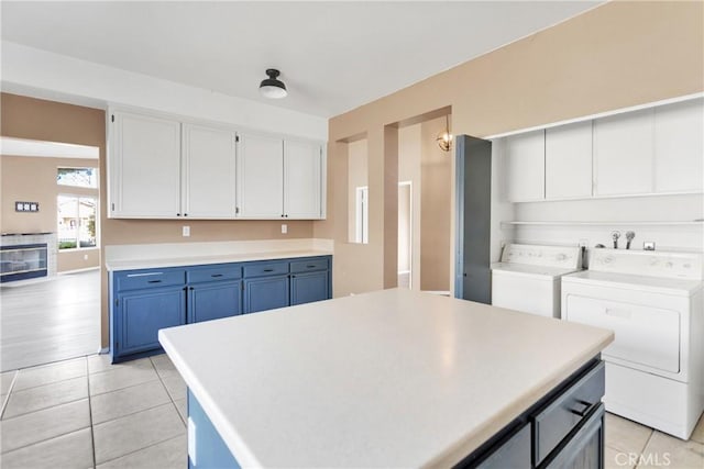 kitchen featuring a kitchen island, white cabinetry, light tile patterned floors, washing machine and clothes dryer, and blue cabinetry