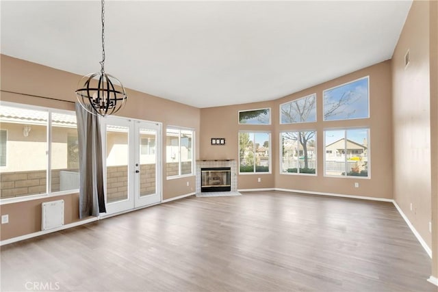 unfurnished living room with hardwood / wood-style floors, a notable chandelier, and french doors