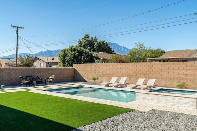 view of pool with a lawn, a mountain view, and an in ground hot tub