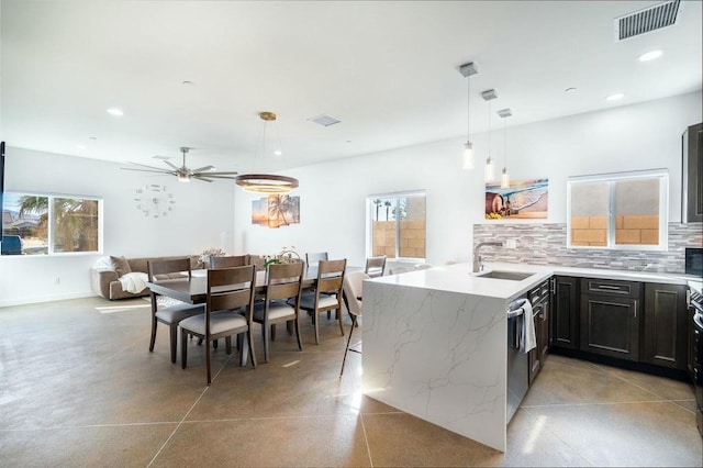 kitchen featuring pendant lighting, sink, ceiling fan, tasteful backsplash, and light stone counters