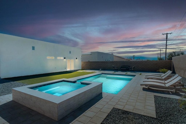 pool at dusk with an in ground hot tub