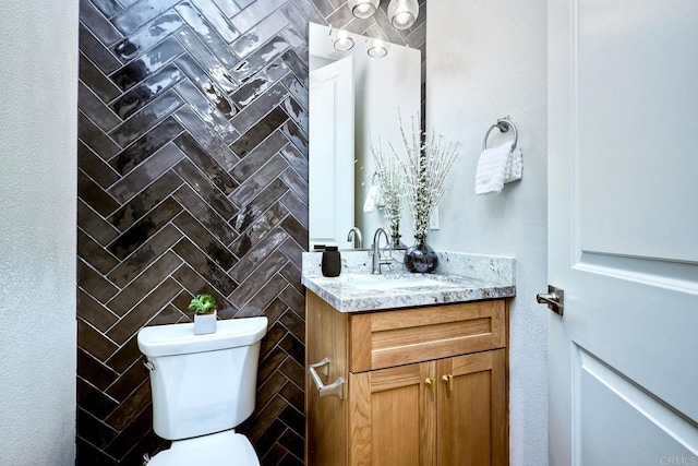 bathroom with vanity, tile walls, and toilet