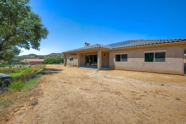 back of house featuring a mountain view, a patio, and solar panels