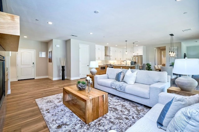 living room with a chandelier, light wood-type flooring, and sink