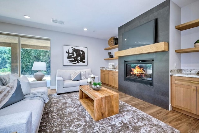 living room featuring a tile fireplace and hardwood / wood-style floors