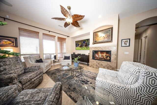 living room featuring ceiling fan, light tile patterned floors, and a tiled fireplace