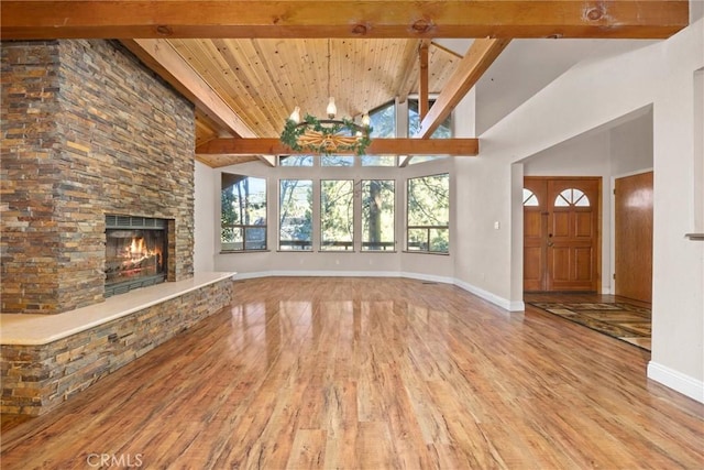 unfurnished living room featuring a fireplace, light hardwood / wood-style floors, beam ceiling, and high vaulted ceiling