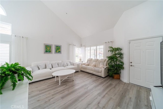 unfurnished living room with high vaulted ceiling and light hardwood / wood-style flooring