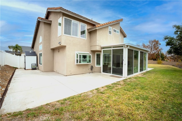 back of property with a patio area, a sunroom, and a lawn