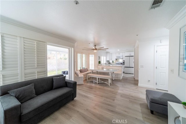 living room with ceiling fan, ornamental molding, and light hardwood / wood-style flooring