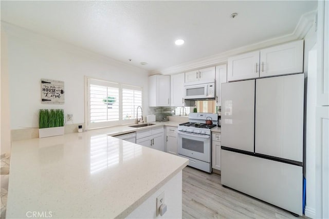 kitchen featuring sink, white appliances, white cabinets, and crown molding