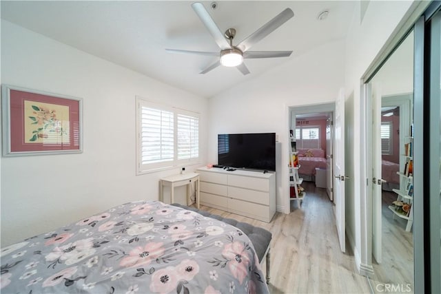 bedroom with ceiling fan, vaulted ceiling, multiple windows, and light hardwood / wood-style floors