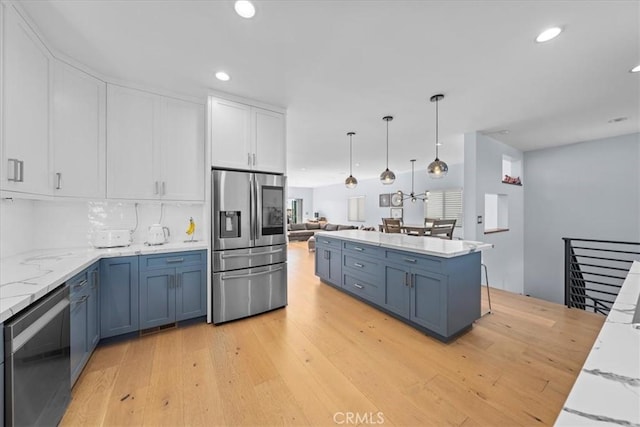 kitchen featuring hanging light fixtures, stainless steel appliances, blue cabinets, light hardwood / wood-style floors, and white cabinets