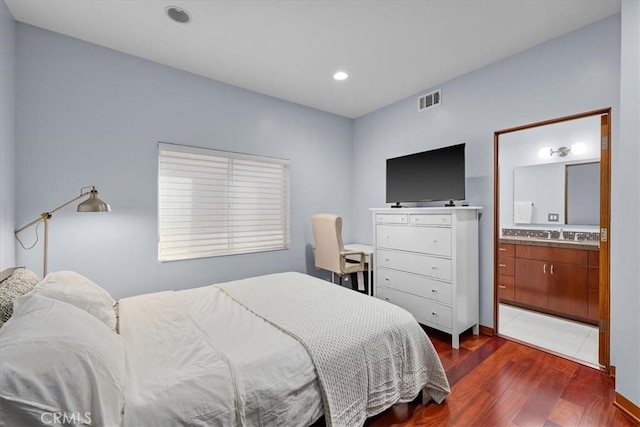 bedroom with ensuite bathroom, dark hardwood / wood-style flooring, and sink