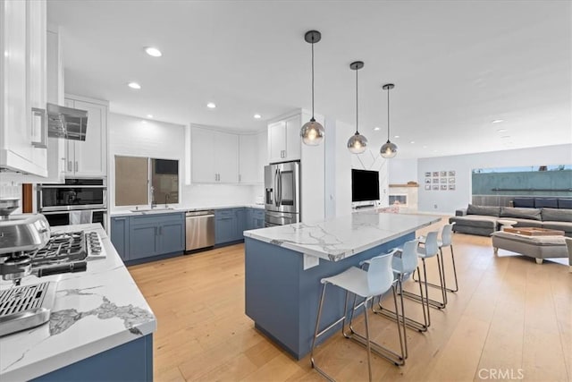 kitchen featuring a center island, pendant lighting, white cabinets, and stainless steel appliances