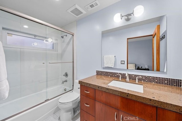 full bathroom with vanity, backsplash, combined bath / shower with glass door, tile patterned flooring, and toilet