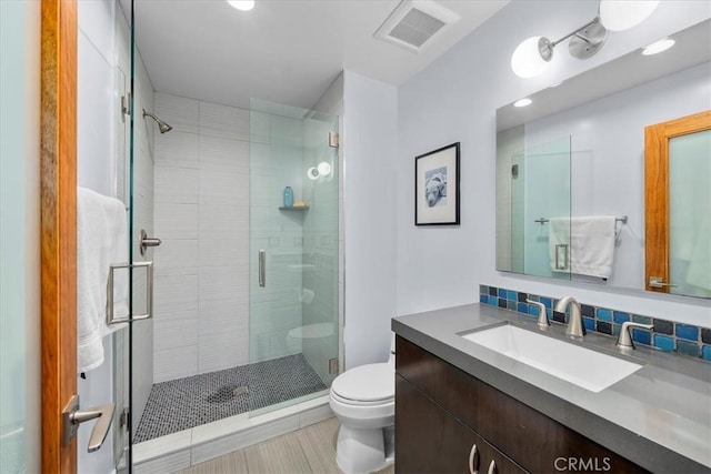 bathroom featuring an enclosed shower, vanity, toilet, and decorative backsplash