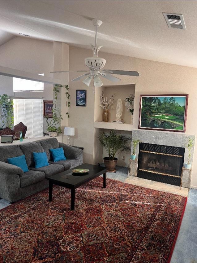 living room with ceiling fan, a fireplace, carpet floors, and lofted ceiling