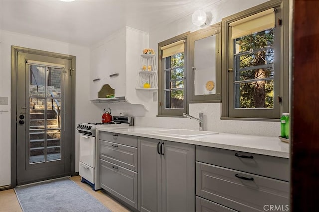 bar with light stone counters, white range oven, gray cabinets, and sink