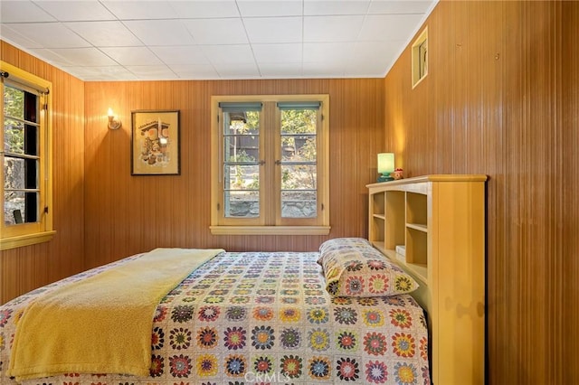 bedroom featuring multiple windows and wooden walls