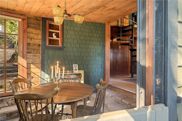 dining space featuring wood ceiling and wooden walls