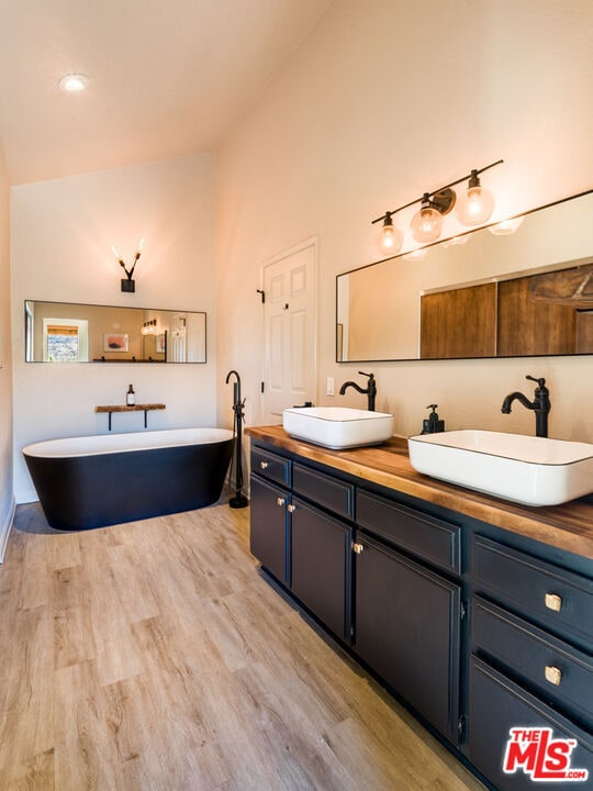 bathroom featuring a bathing tub, vanity, wood-type flooring, and high vaulted ceiling