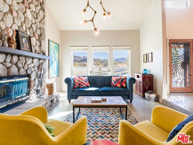 living room with a chandelier, a stone fireplace, and vaulted ceiling